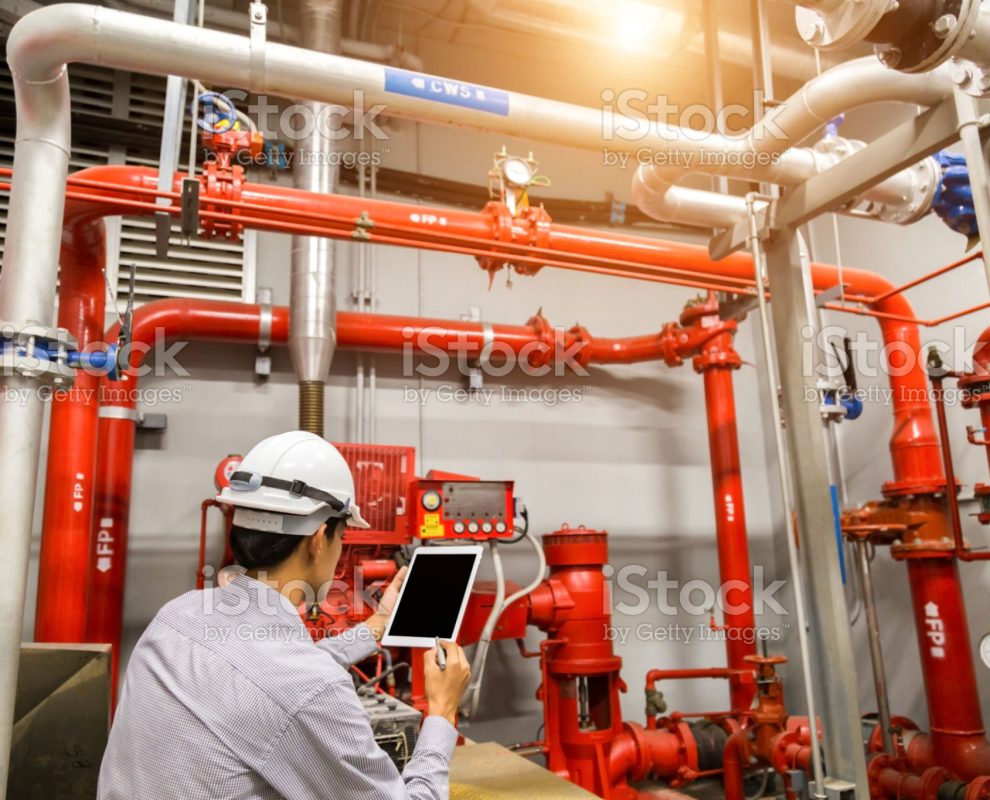 Engineer with tablet check red generator pump for water sprinkler piping and fire alarm control system.